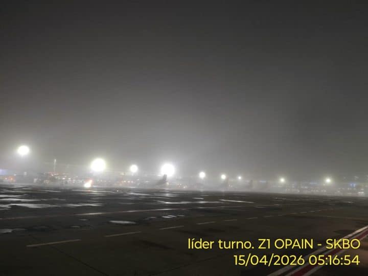 Pasajeros en el Aeropuerto El Dorado rodeados de mal tiempo y pantallas de vuelos con retrasos.