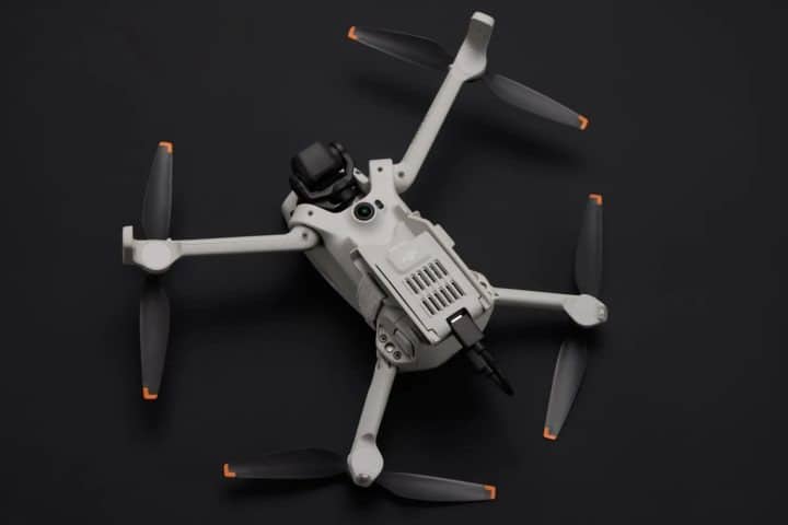 Un dron Lito X1 vuela sobre un paisaje verde, mientras un principiante lo controla con una sonrisa.