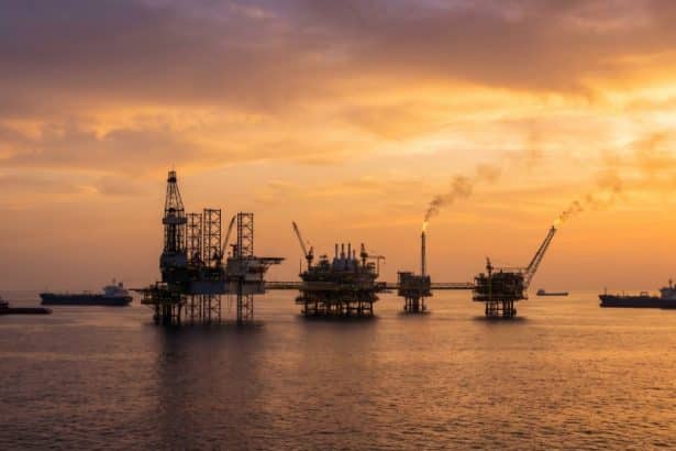 Plataformas petroleras en el golfo Pérsico al atardecer, con barcos de suministro en primer plano.