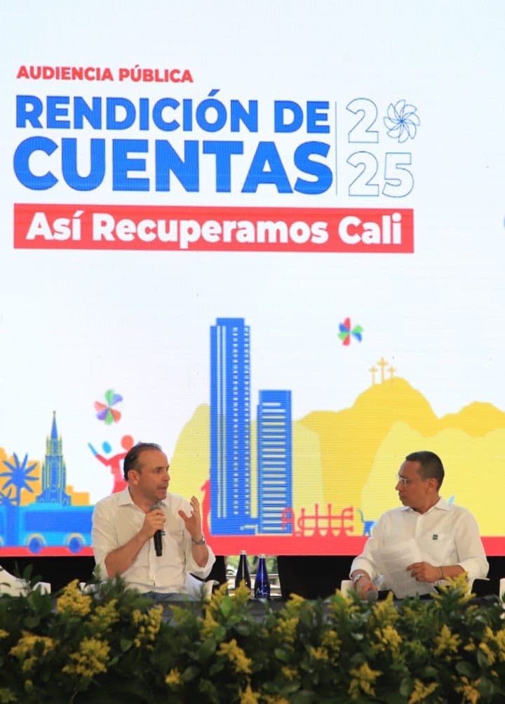 Un grupo de ciudadanos escucha atentamente a los panelistas en la audiencia pública, con micrófonos y pantallas detrás.