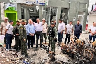 Un grupo de personas se reúne en un monumento en La Plata, con flores y velas en memoria de las víctimas.