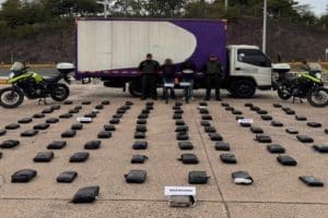 Dos agentes de policía sostienen bolsas con marihuana incautada en un operativo en la carretera del Cesar.