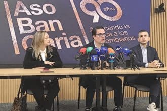El presidente de Asobancaria habla en una conferencia, con gráficos de deudas en la pantalla detrás.