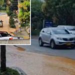 Calle inundada en Envigado, con vehículos atrapados y residentes preocupados.