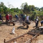 Grupo de jóvenes indígenas trabajando en la construcción de una vía rural en Paniquita bajo un cielo despejado.