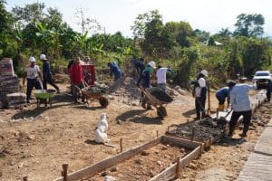 Grupo de jóvenes indígenas trabajando en la construcción de una vía rural en Paniquita bajo un cielo despejado.