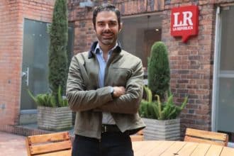 Una mujer sonriente revisa su celular en una cafetería, con un logo de Addi visible en la mesa.