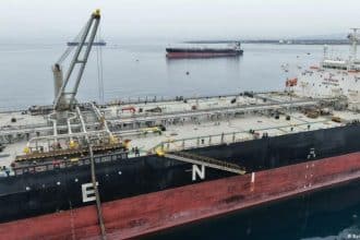 Un grupo de diplomáticos se reúne en una mesa con documentos y laptops en un ambiente formal.