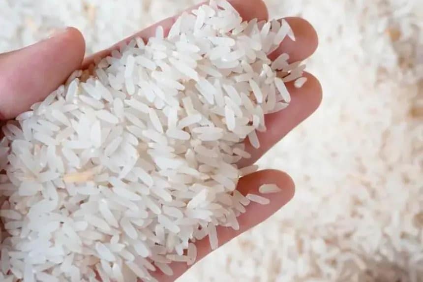 Un saco de arroz y varios paquetes de harina sobre una mesa de madera.