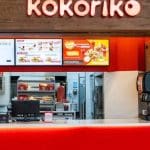 Logo de Kokoriko en un restaurante vacío, mostrando un menú de pollo asado.