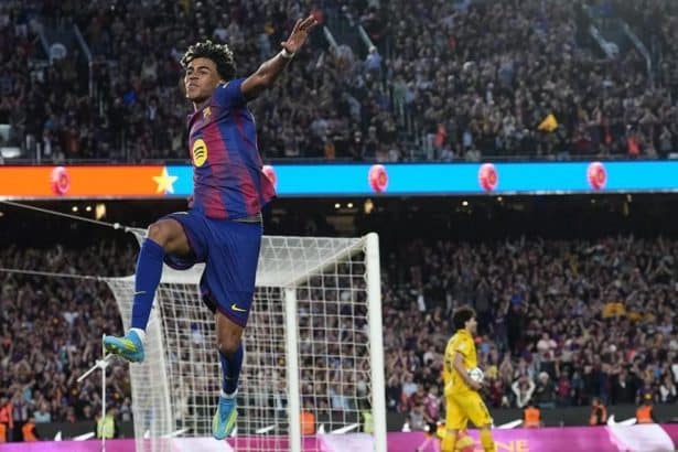 Lamine Yamal celebrando su gol en el derbi, con aficionados animando de fondo.