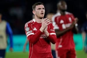 Jugadores de Liverpool celebran un gol en Anfield, con aficionados animando en las gradas.