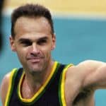 Oscar Schmidt sonriendo en la cancha, con su camiseta de Brasil y el balón de baloncesto en mano.