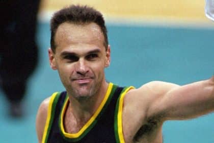 Oscar Schmidt sonriendo en la cancha, con su camiseta de Brasil y el balón de baloncesto en mano.