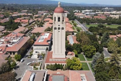 La Universidad de Stanford con su arquitectura emblemática y estudiantes caminando por el campus.