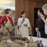 Piezas arqueológicas agustinianas en mesas, con personas observando atentamente.