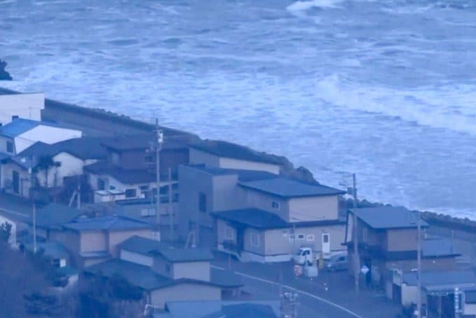 Olas golpean el puerto de Kuji, con escombros y evacuaciones visibles en la costa.
