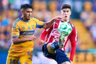 Jugadores de Tigres celebran un gol en el Estadio Universitario, con la afición vitoreando al fondo.
